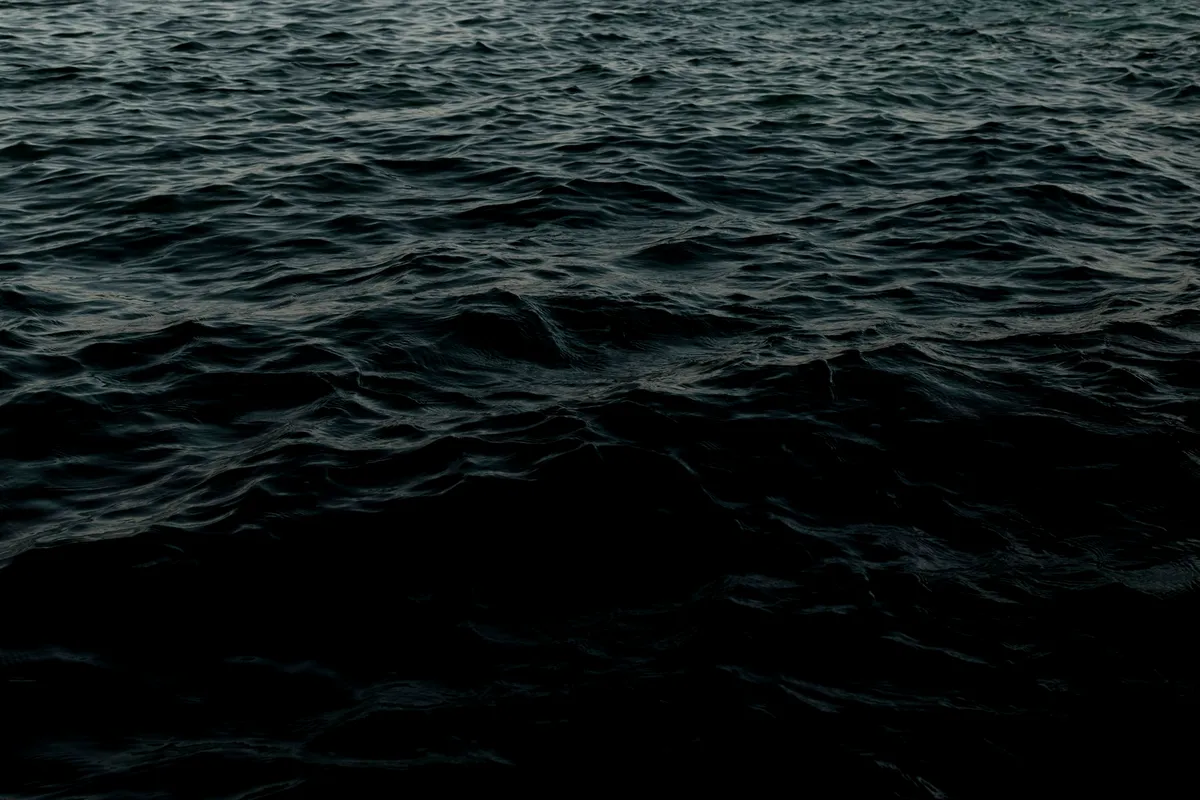 Dark deep-ocean water fading into black